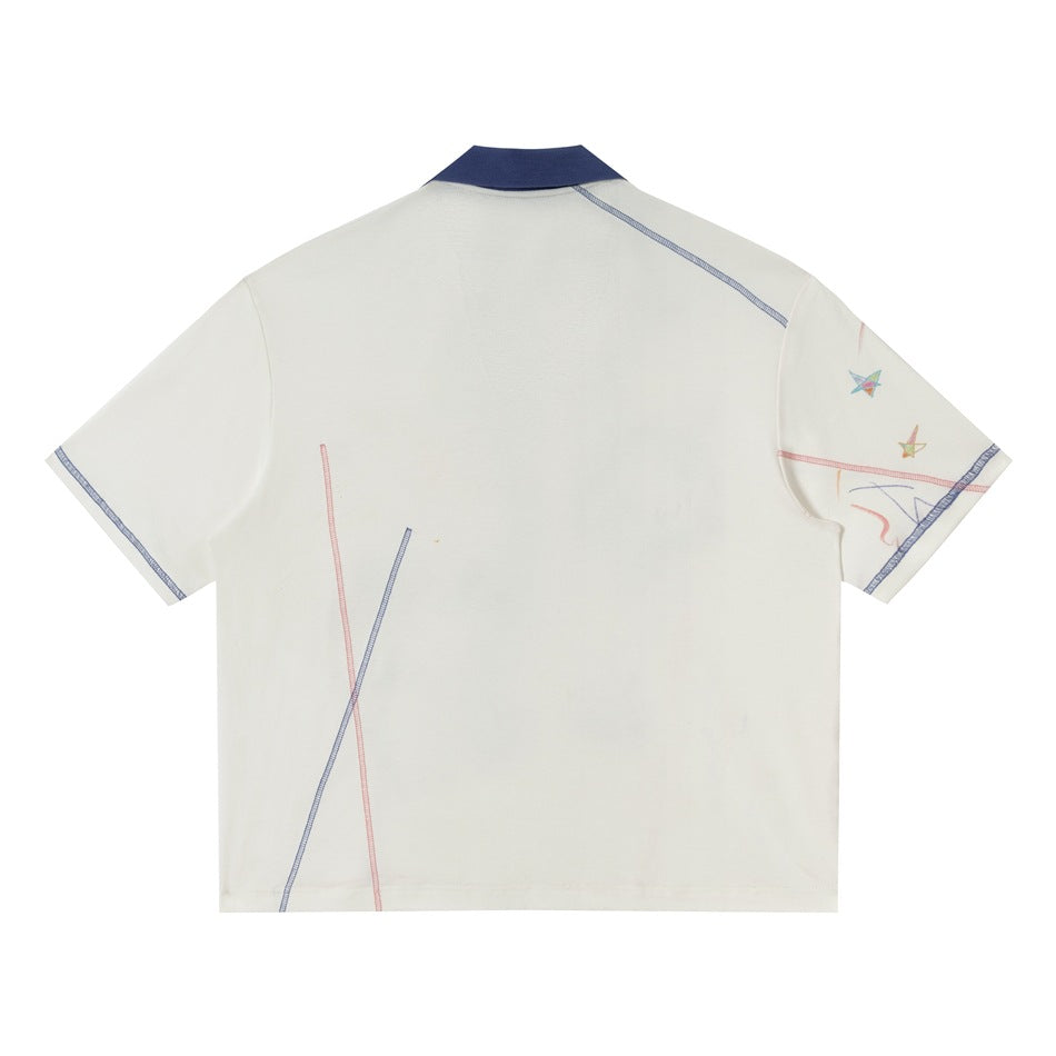 Back of white polo top with navy collar, blue and pink contrast stitched lines and a small star print on the sleeve