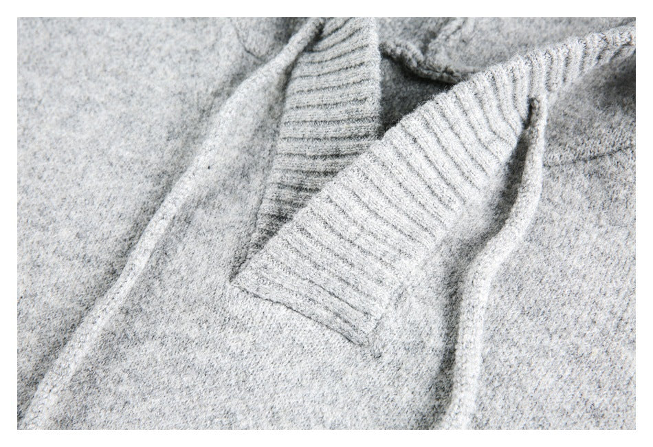 Close-up of a light gray knit garment showing a ribbed trim and nearby seams.