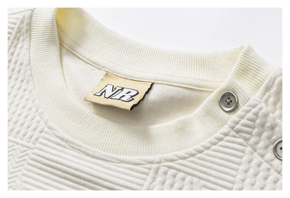 Close-up of the ivory pullover's crew neckline, inner NB label, and buttoned shoulder placket.