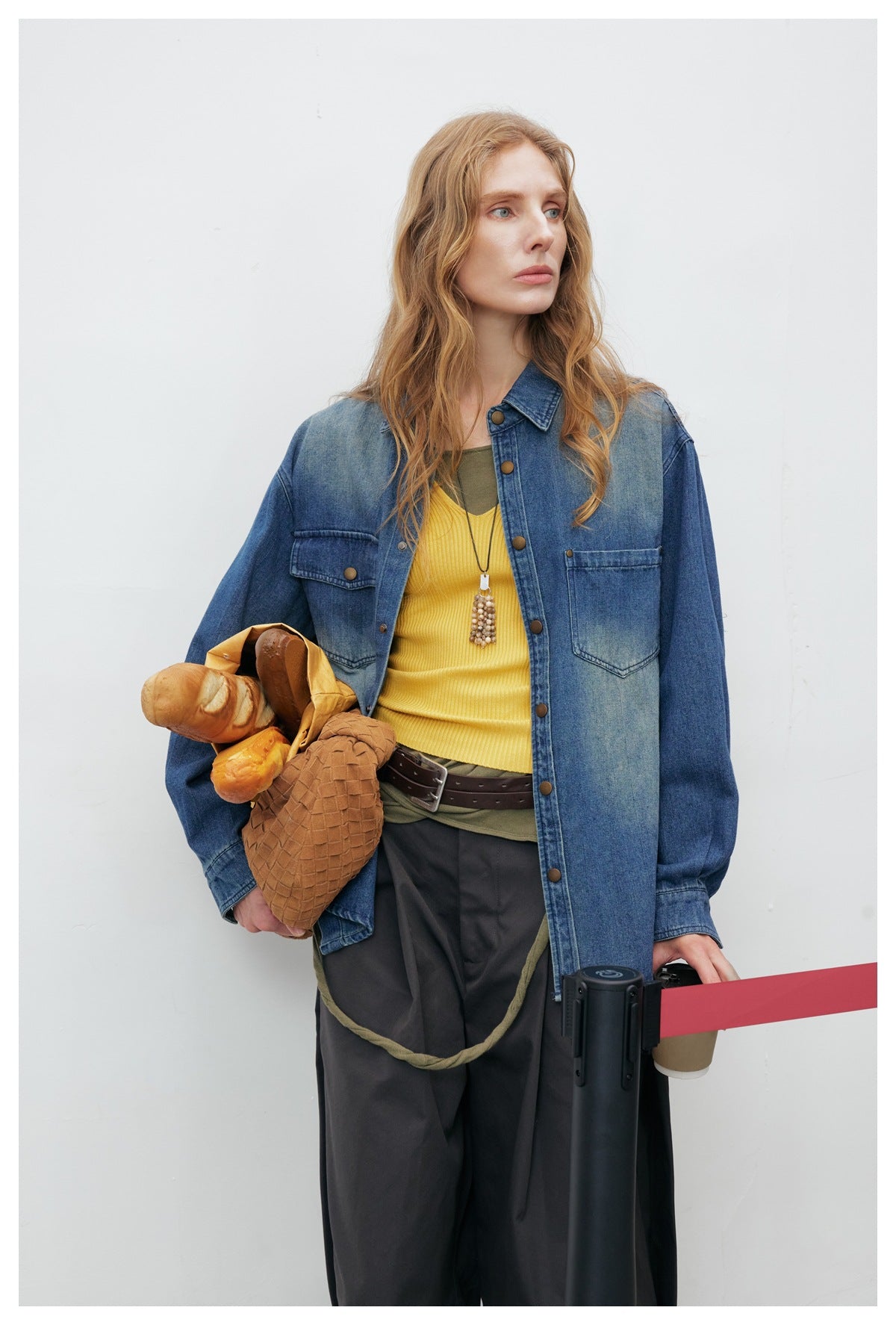Closer front view of a model wearing a blue denim shirt with a pointed collar and two chest pockets.