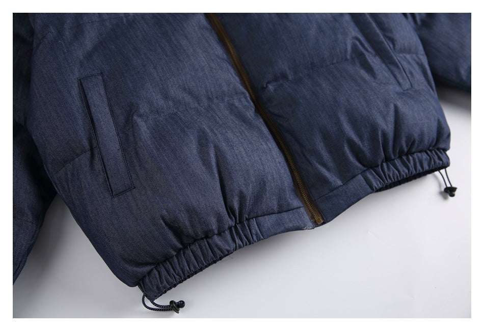 Close-up of a dark blue jacket's front zipper, welt pocket, and elasticized hem with drawcords.