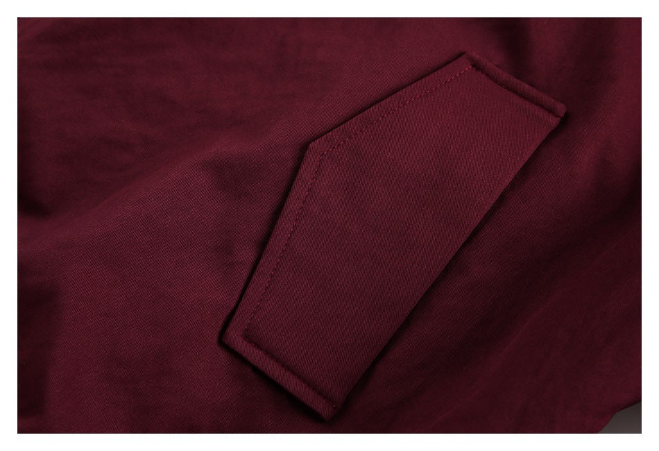 Close-up of a burgundy jacket's stitched flap pocket.