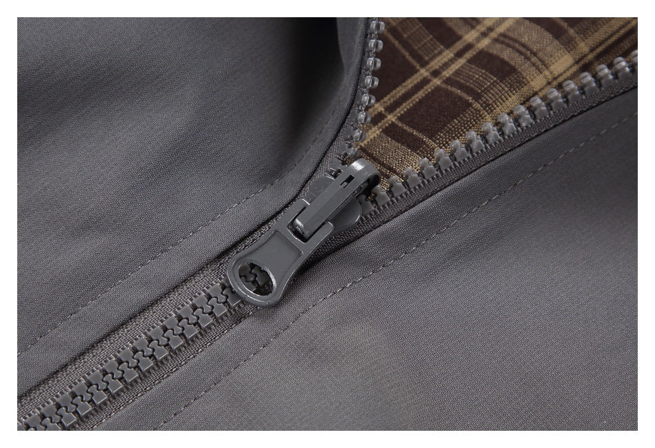 Close-up of a dark gray garment zipper with chunky teeth and a brown plaid fabric accent.
