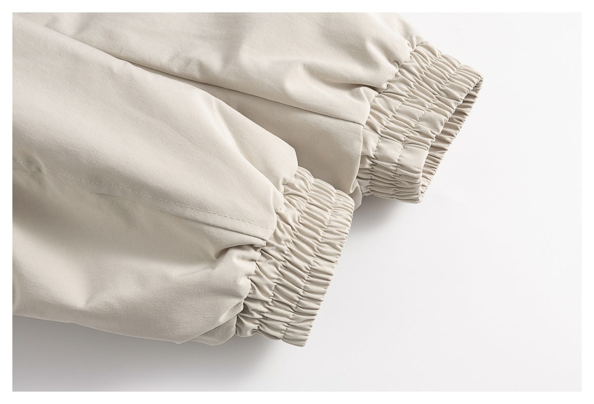 Close-up of two gathered elastic cuffs on light beige sleeves.