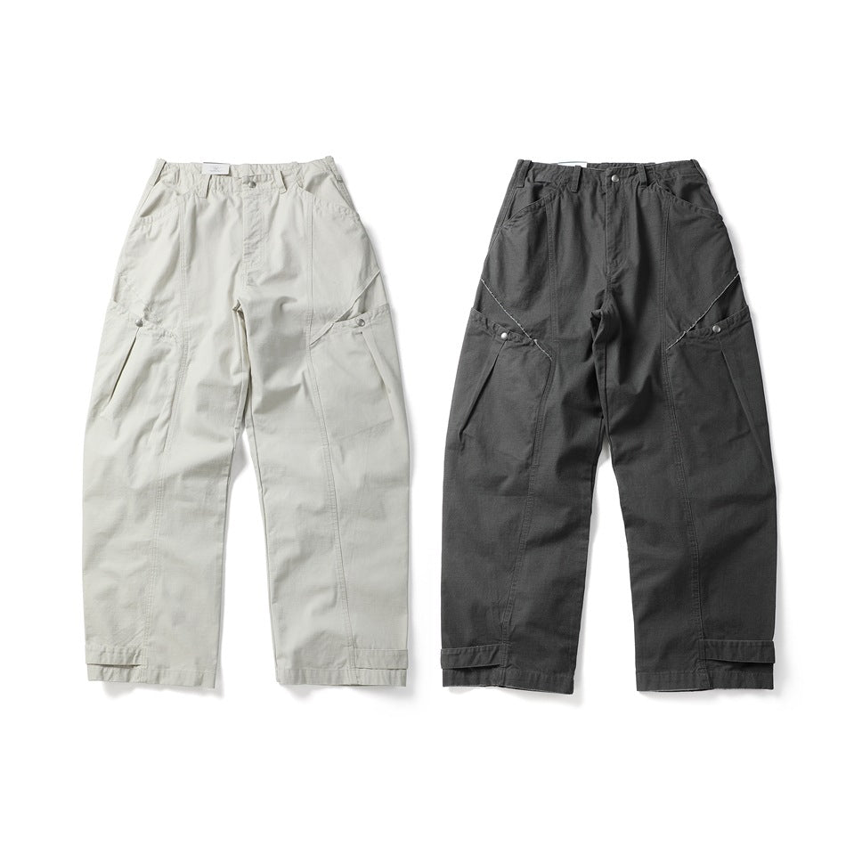 Two pairs of utility pants shown from the front in light cream and charcoal gray, with angled panels and snap tabs.