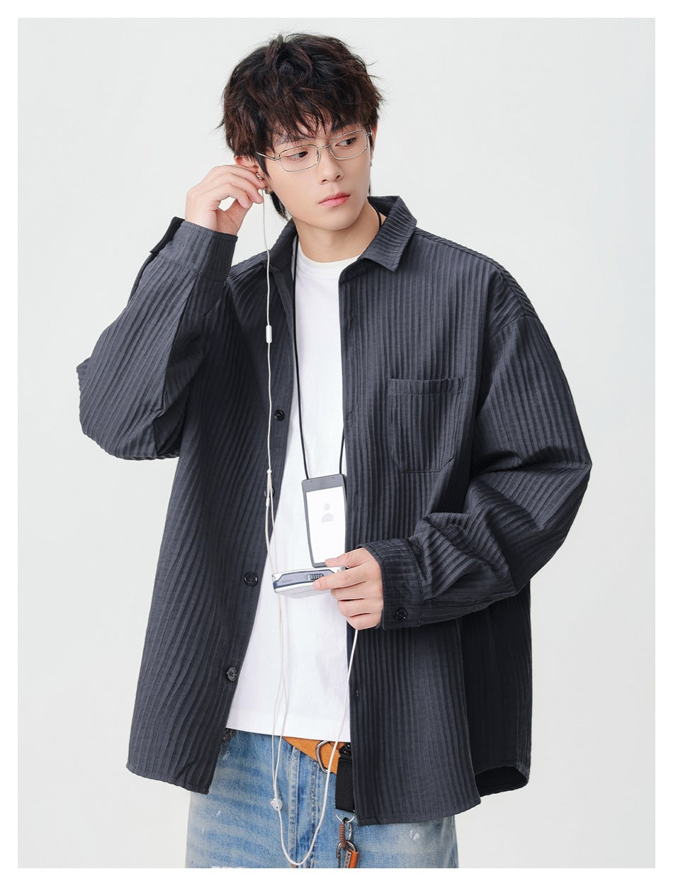 Model wearing an oversized charcoal ribbed button-up shirt, shown from the front with the shirt open over a white tee.