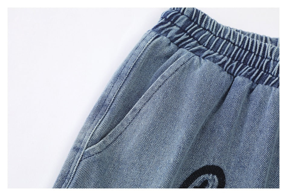 Close-up of a curved side pocket and elastic waistband on blue denim shorts.