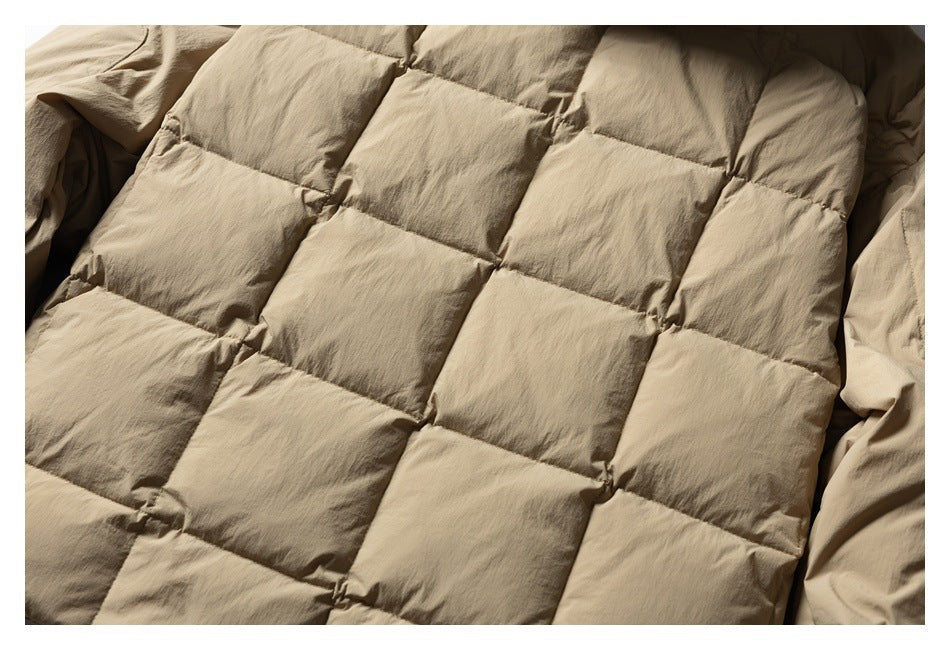 Close-up of the tan jacket's large square quilted padding and stitched seams.