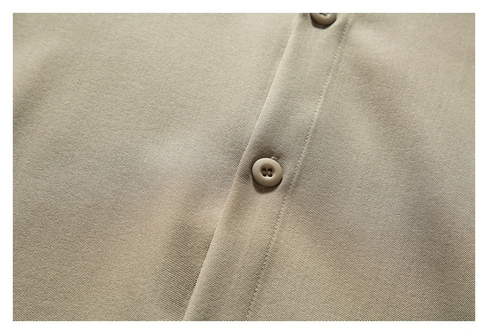 Close-up of a beige garment's button placket with two matching buttons and visible stitching.
