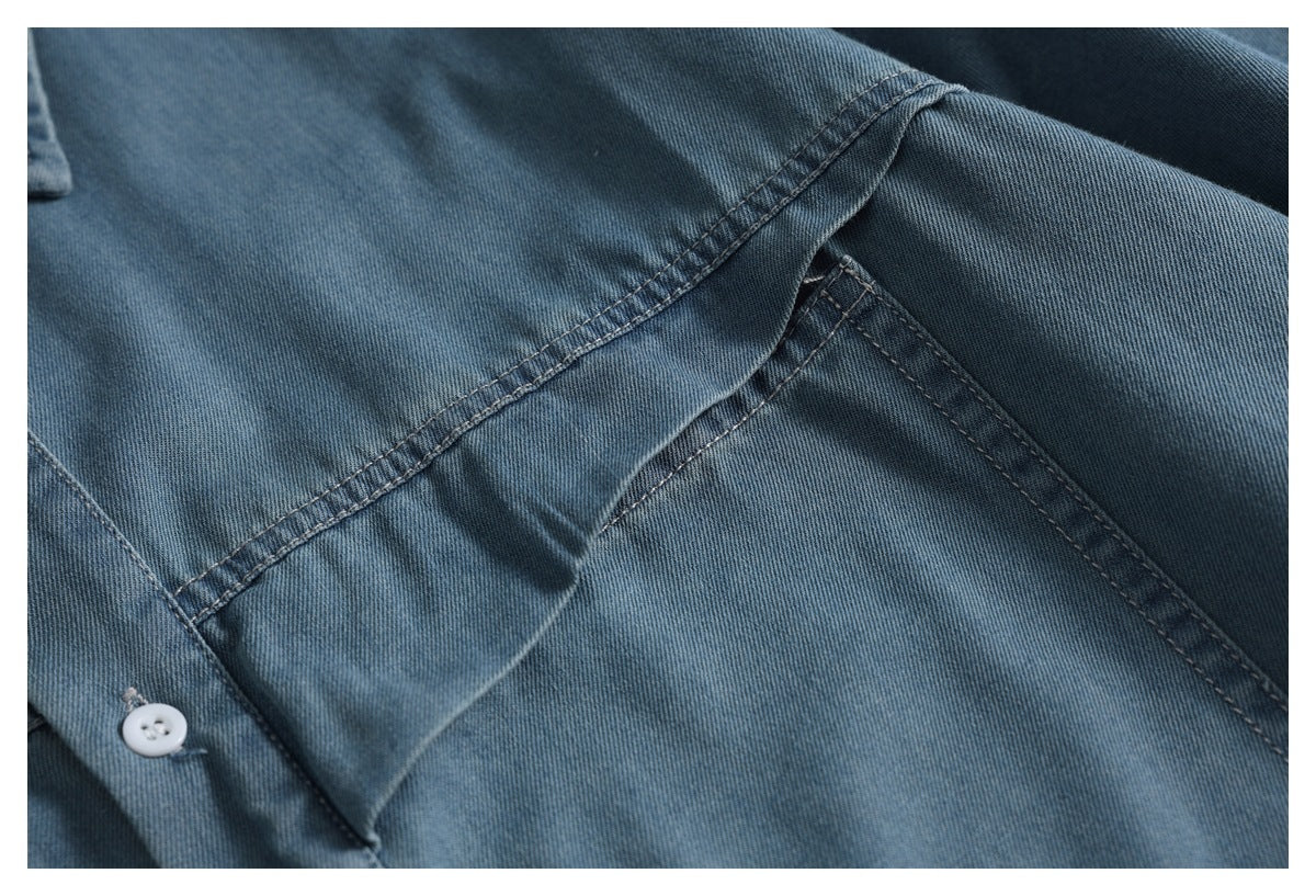 Close-up of a blue denim shirt pocket and intersecting stitched seams.