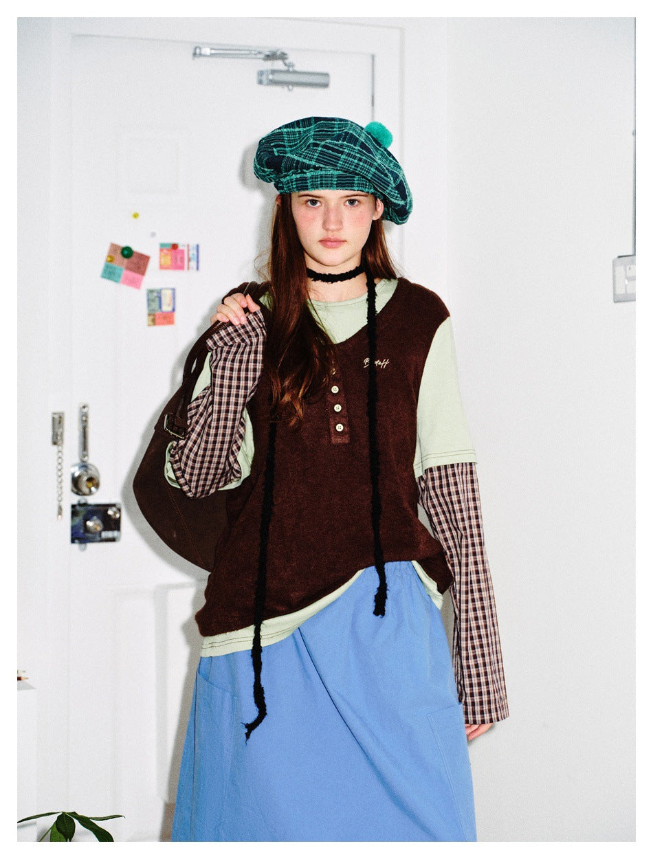 Model in the coffee brown Henley layered top with plaid sleeves, blue skirt, green plaid beret and brown bag