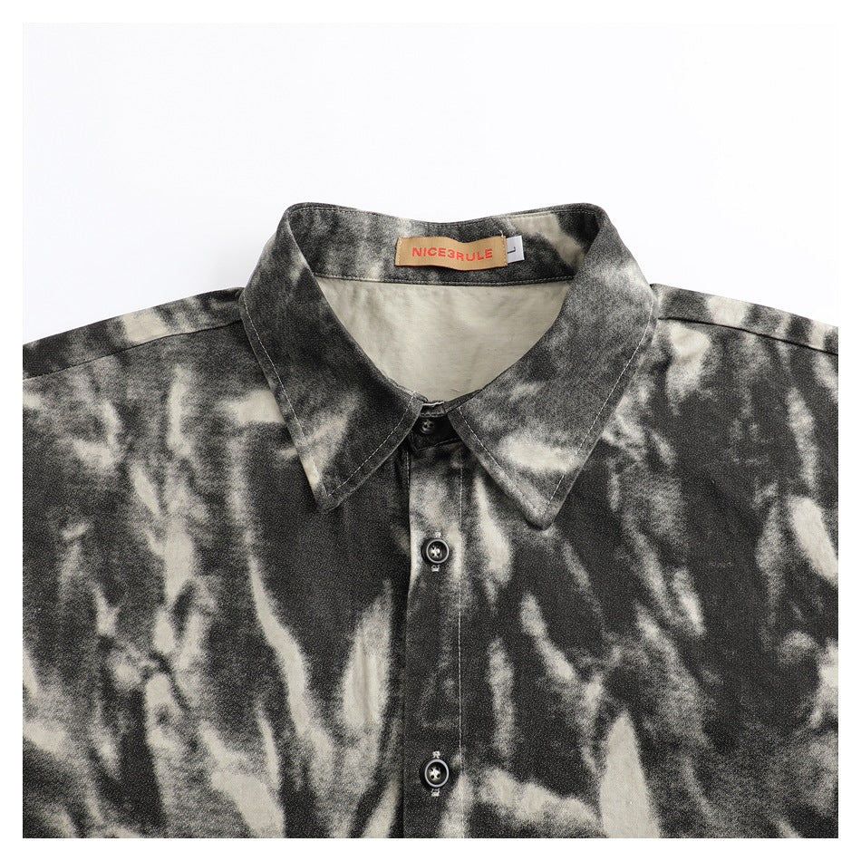 Close-up of a black and cream abstract-patterned shirt collar, button placket, and sewn neck label.
