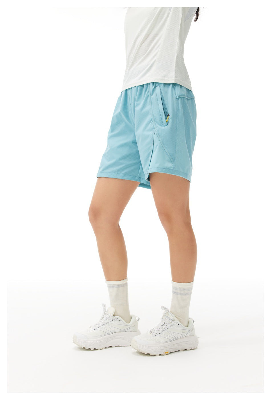 Side view of a model wearing light blue athletic shorts with a side pocket and white short-sleeve shirt.