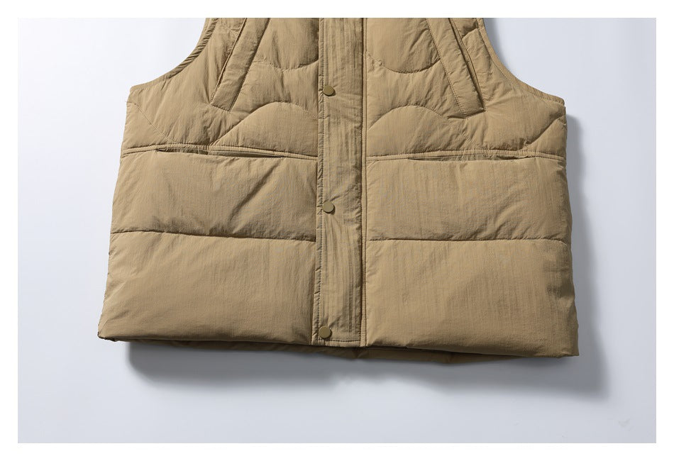 Cropped lower-front view of a tan quilted vest, showing horizontal panels and snap closures.