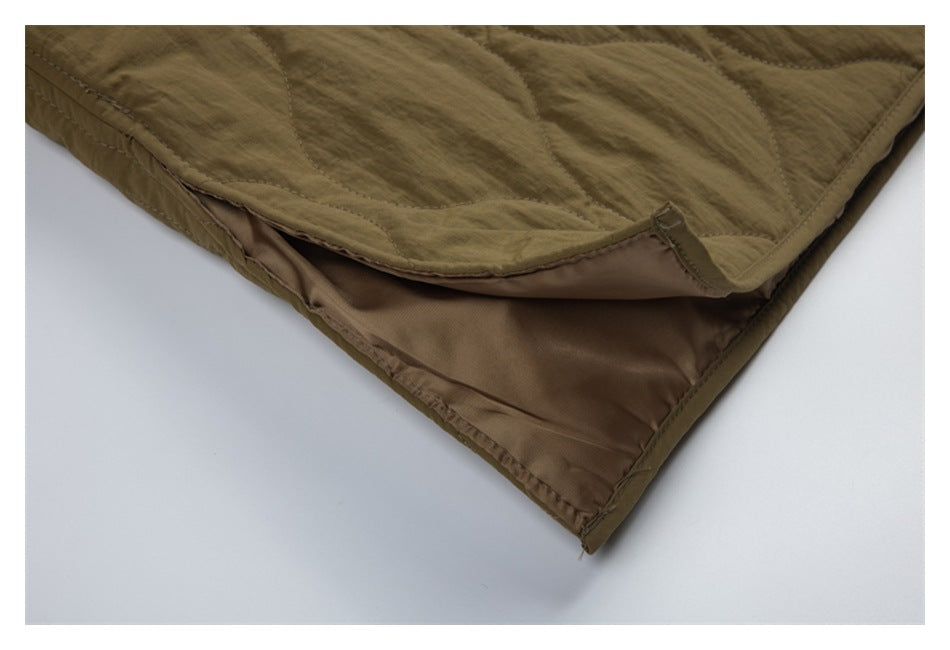 Close-up of the olive-brown quilted jacket hem, showing its brown lining and finished edge.
