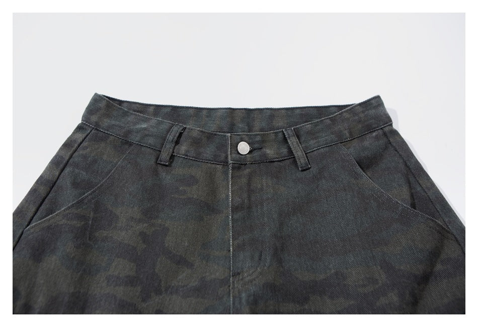 Front waistband close-up of dark charcoal camouflage pants with a button, belt loops and angled pockets.