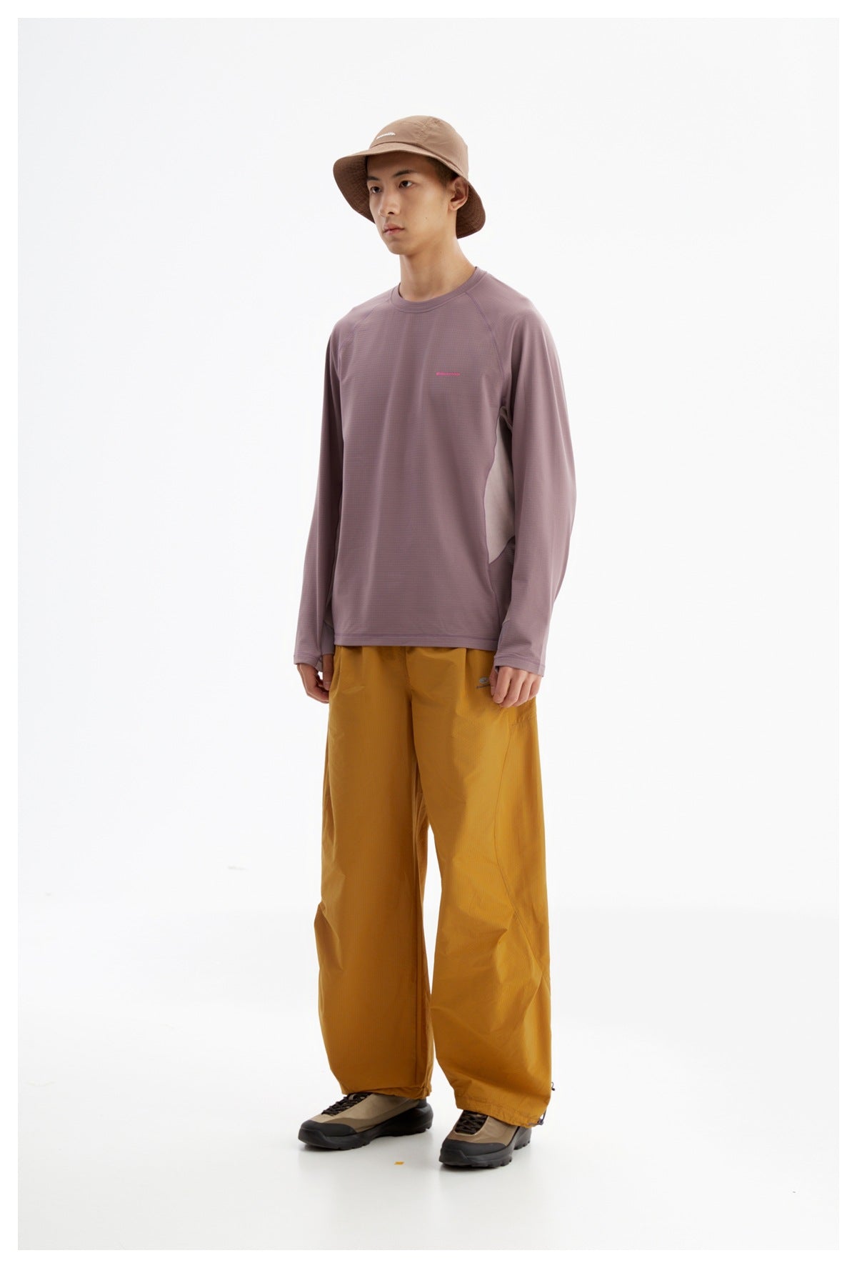 Model wearing a mauve long-sleeve crewneck shirt, mustard wide-leg pants, and a brown bucket hat.