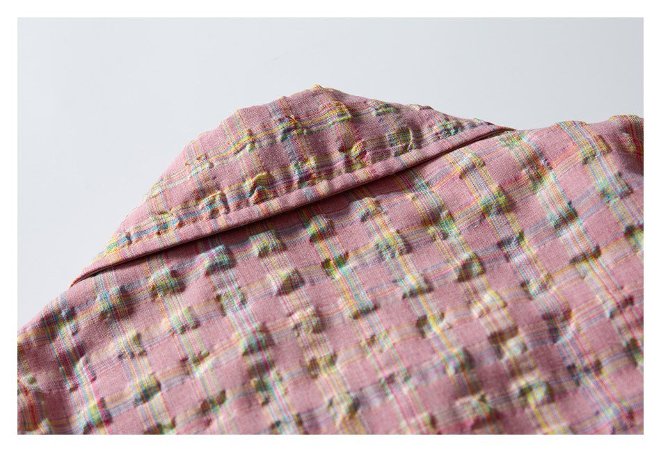 Close-up of a pink plaid garment showing a folded collar or lapel and textured fabric.