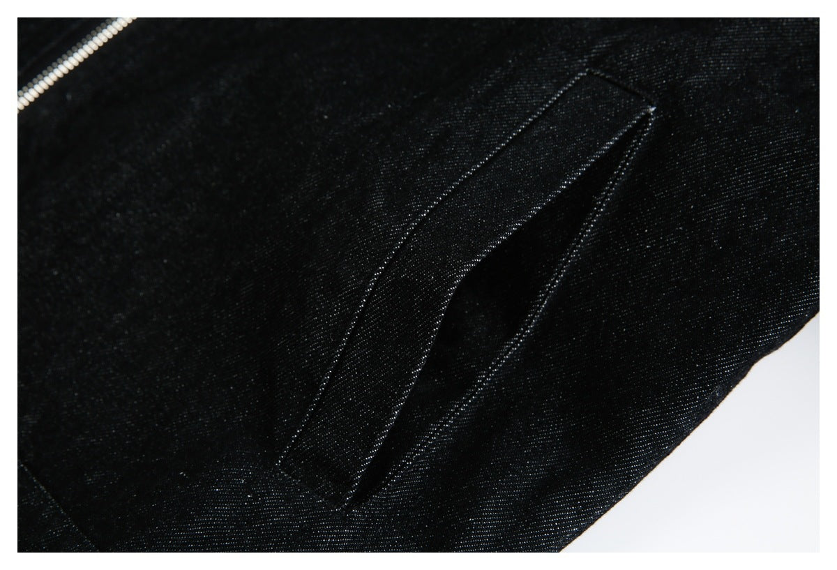 Close-up of black fabric showing a zipper edge and a long stitched flap or pocket detail.