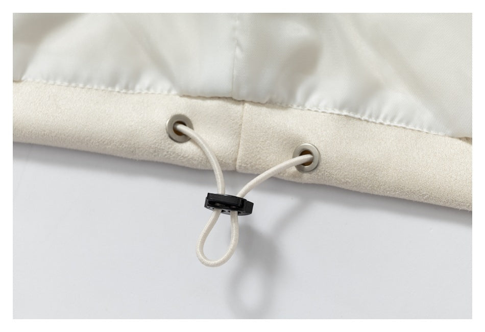 Close-up of an ivory garment hem with metal eyelets and an adjustable elastic drawcord.