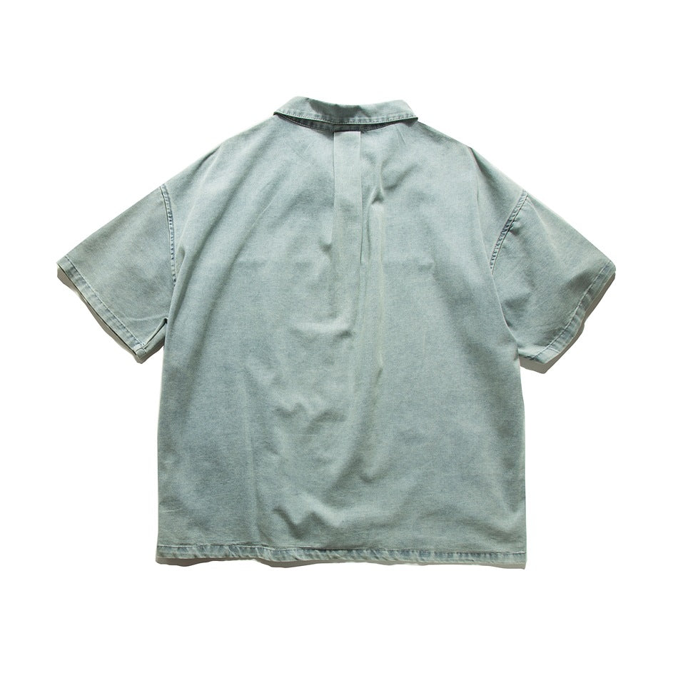 Back view of washed light blue-green short-sleeve shirt with center pleat below collar, flat lay