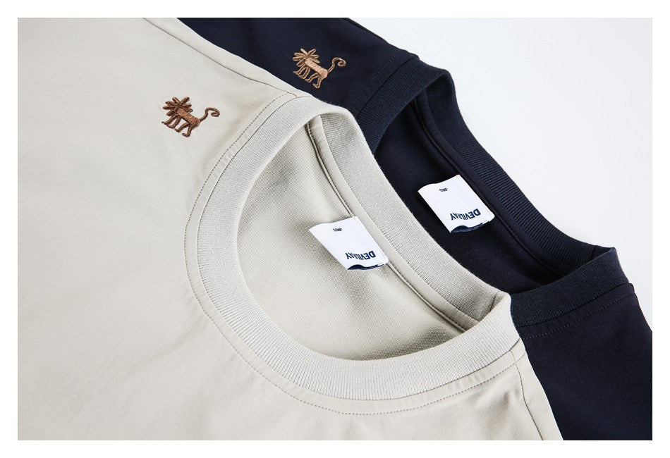 Close-up of beige and navy T-shirt necklines with ribbed collars and small embroidered animal motifs.