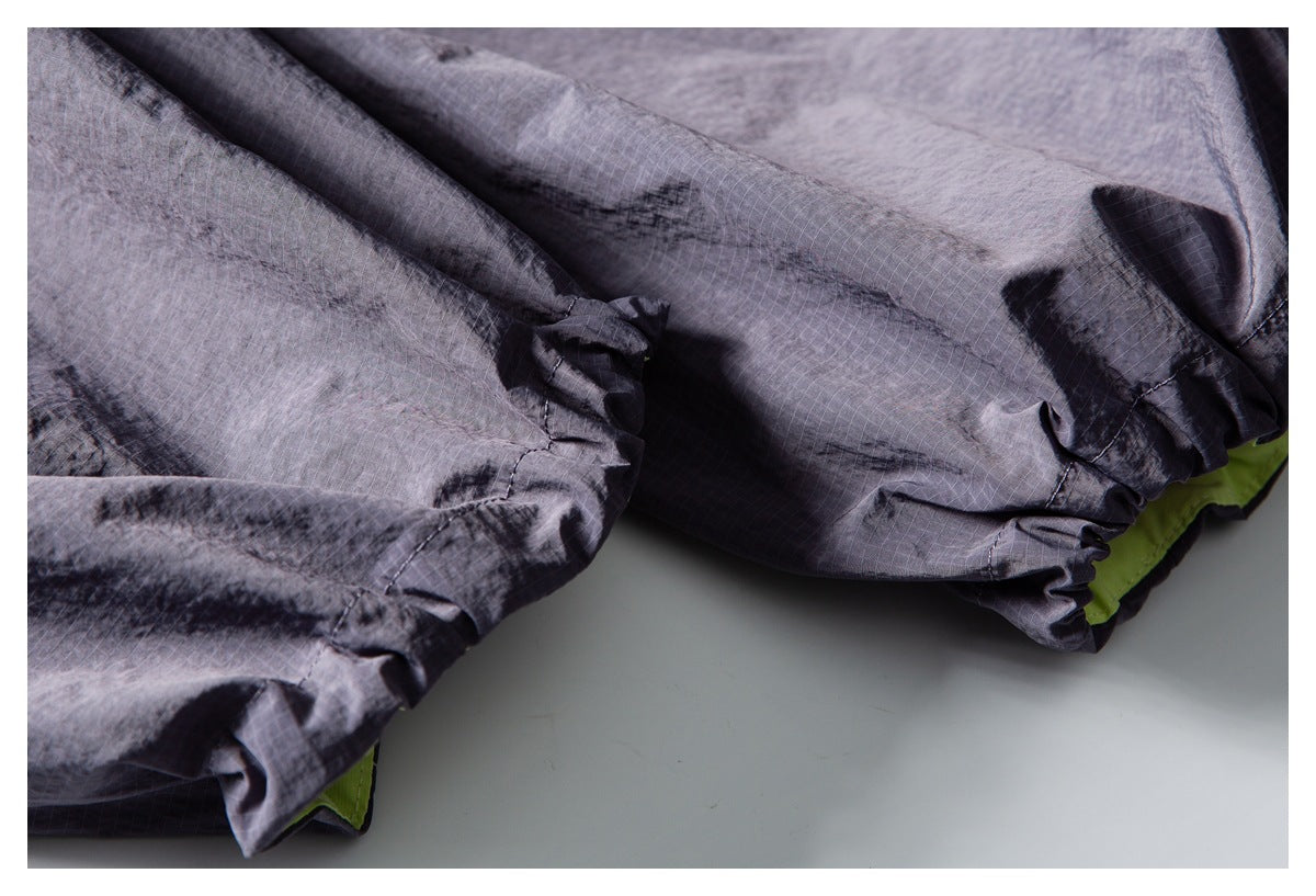 Close-up of charcoal-gray garment with gathered elastic edges and a bright lime-green layer peeking beneath.