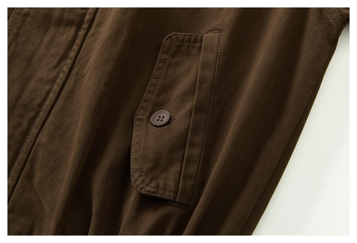 Close-up of a dark brown jacket sleeve's buttoned cuff tab and stitching.