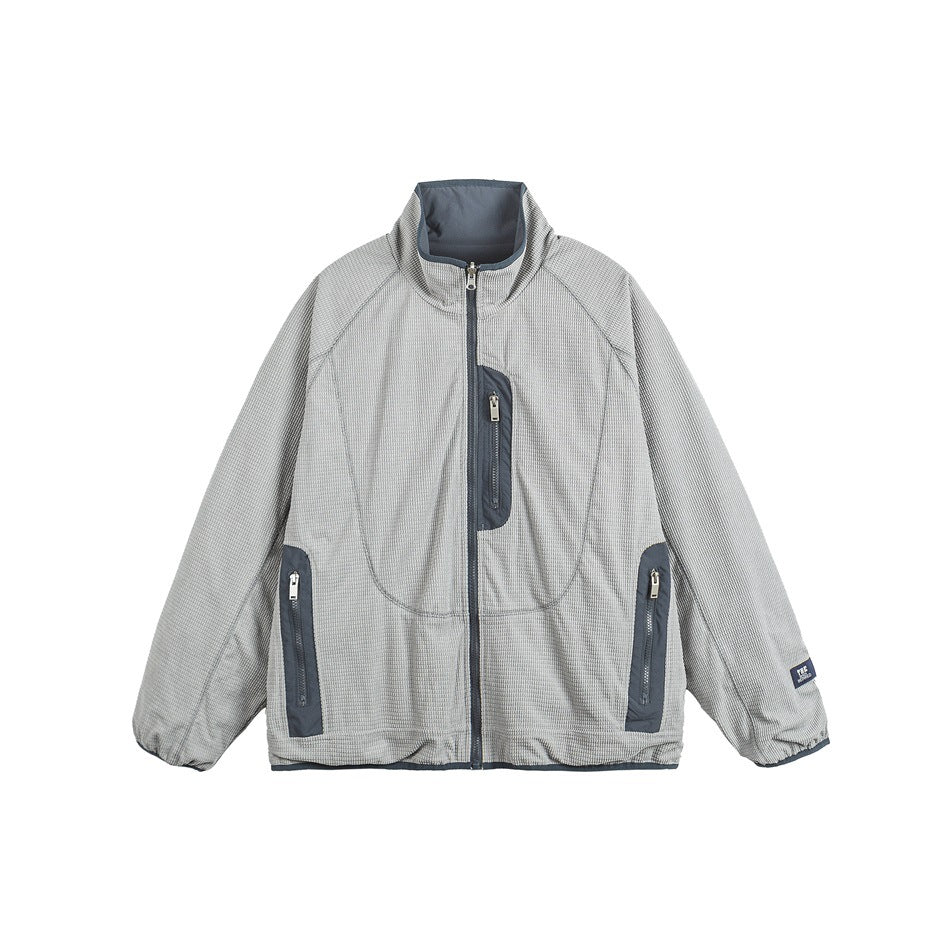 Gray waffle-textured zip jacket with stand collar, blue-gray trim and zip pockets, flat front view