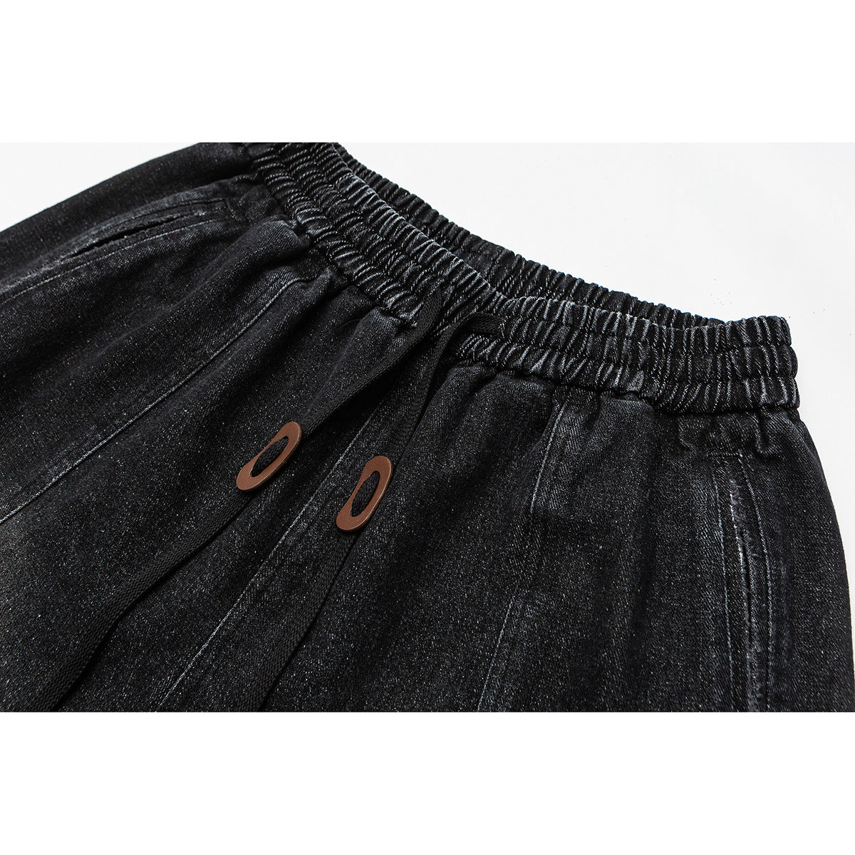 Close-up of black pants with a gathered elastic waistband and two brown oval accents.