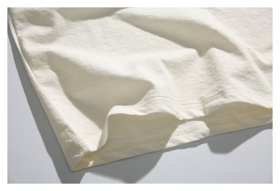 Close-up of the ivory top's folded lower hem and fine ribbed fabric texture.