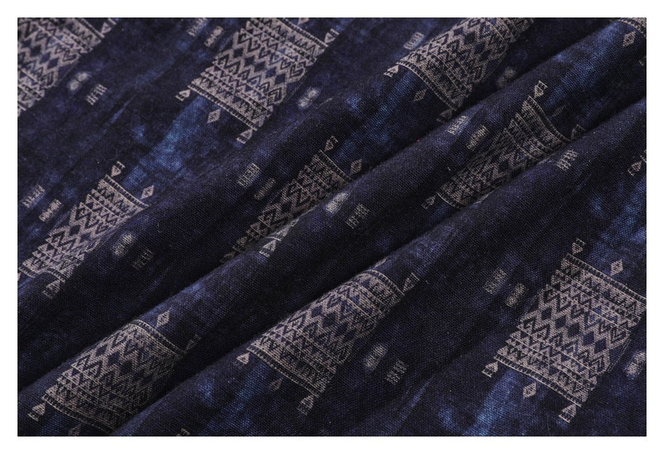 Close-up of navy fabric with repeating tan geometric motifs and visible folds.