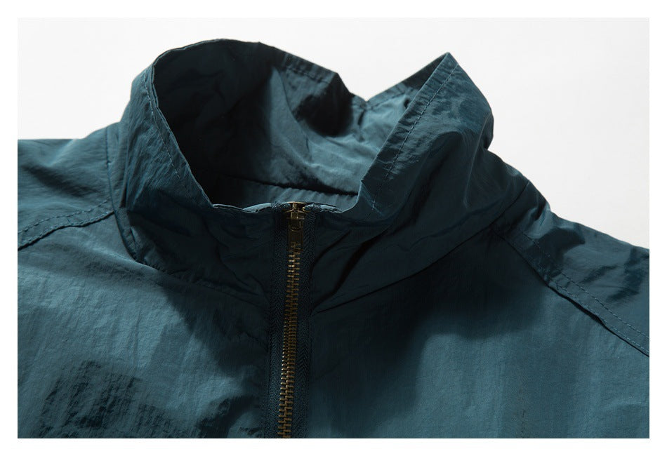 Close-up of the dark teal jacket's tall collar and brass-tone front zipper.