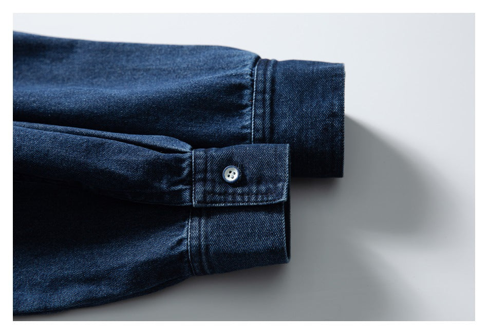 Close-up of a dark indigo denim shirt cuff with a small button and visible stitching.