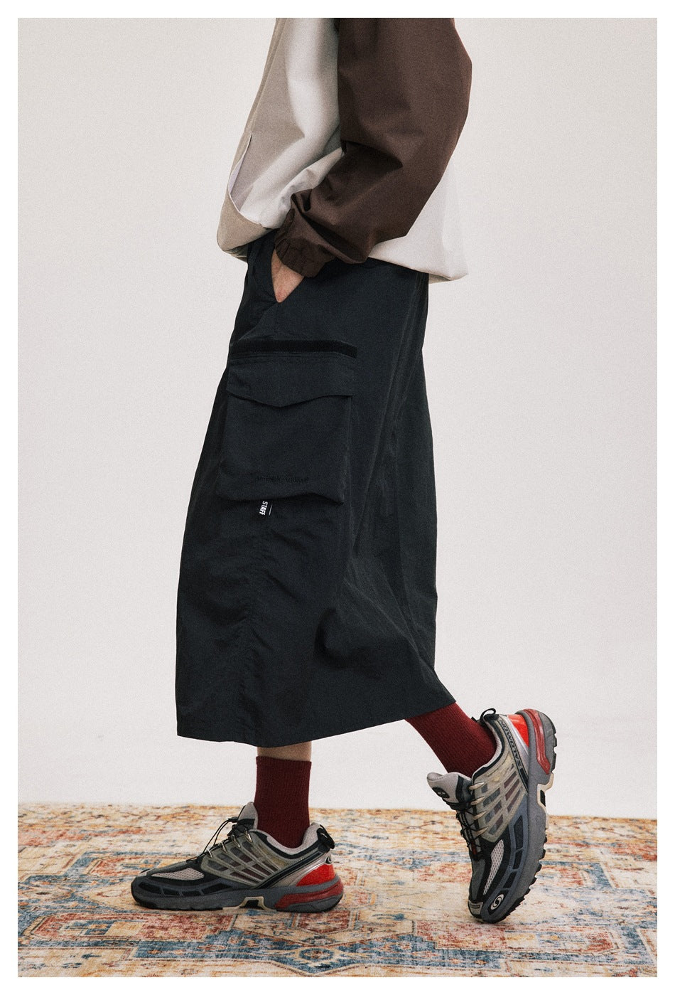 Side view of a person wearing a black midi cargo skirt with a large flap pocket, red socks and sneakers