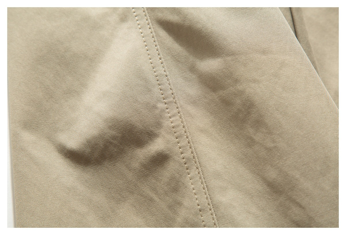 Extreme close-up of light beige pants fabric with a diagonal line of double stitching.