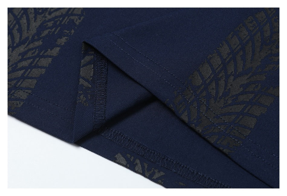 Close-up of a navy garment's folded hem and overlocked stitching, with a dark repeating pattern.