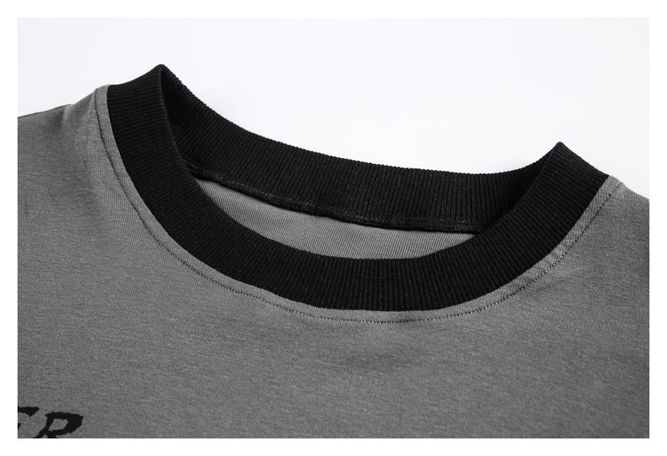 Close-up of a gray top's wide black ribbed crew neckline and shoulder seam.