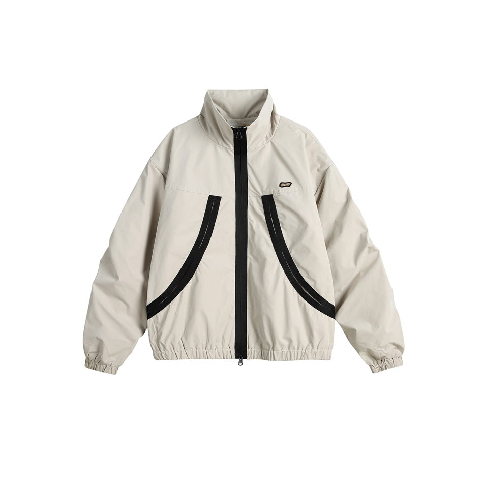 Beige stand-collar zip jacket with black curved tape trim, elastic cuffs and hem, flat front view