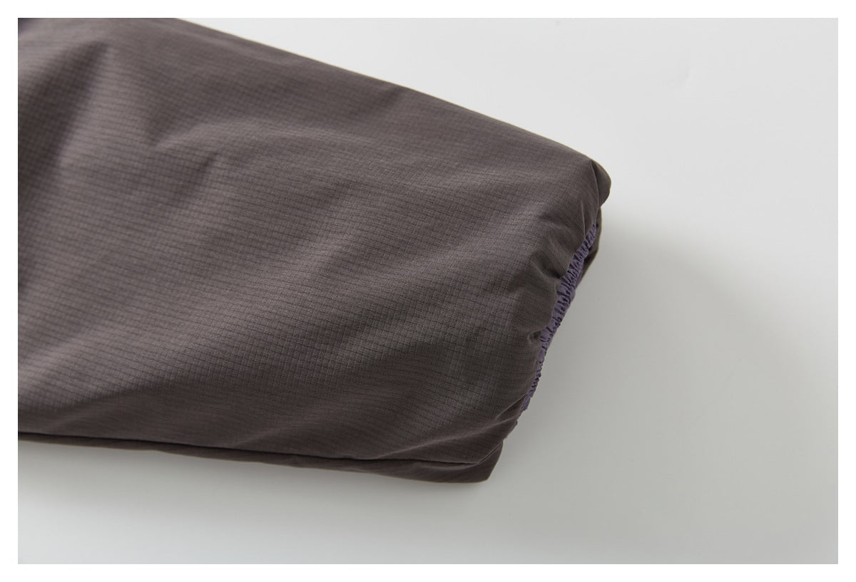 Close-up of a dark charcoal jacket sleeve ending in a gathered cuff.