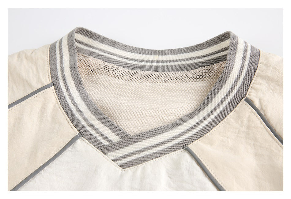 Close-up of a cream top's striped gray V-neck ribbing and mesh inset.