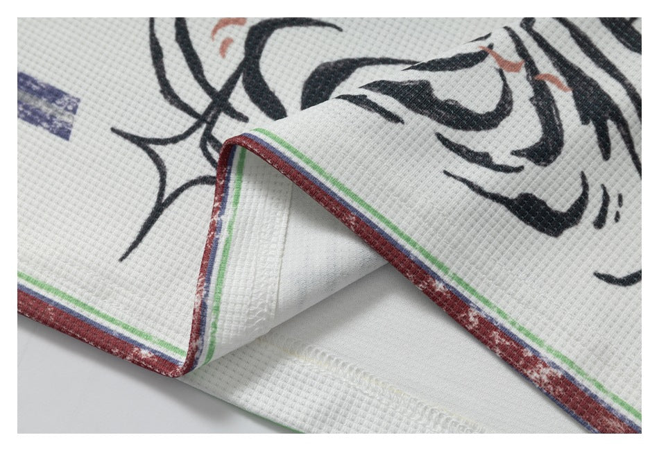 Close-up of black abstract print beside a folded white fabric edge with red, green and navy stripes.