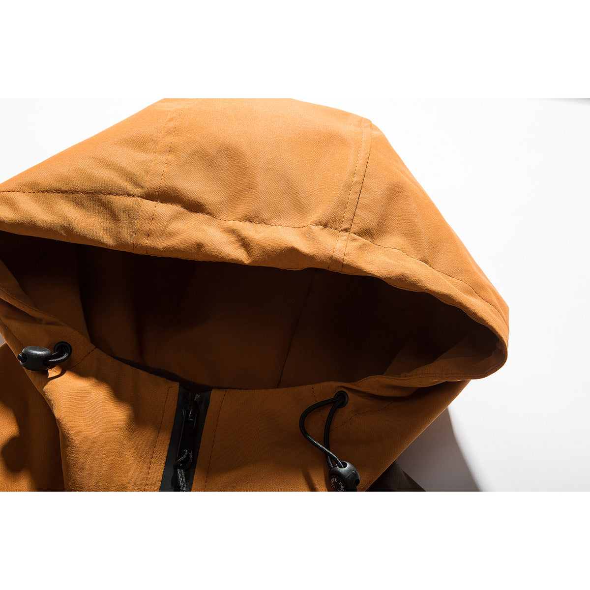 Close-up of an orange jacket hood with black drawcord toggles and the front zipper.