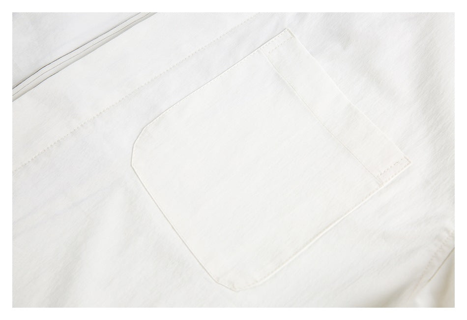 Close-up of a large stitched patch pocket on an ivory garment.
