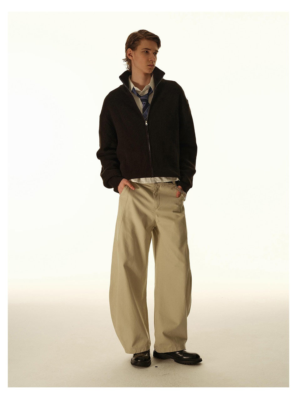 Full-length front view of a model in a dark ribbed zip-up cardigan and wide beige trousers.
