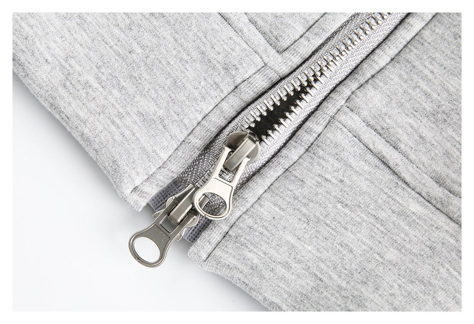 Close-up of a silver two-way zipper on light gray heathered fabric.