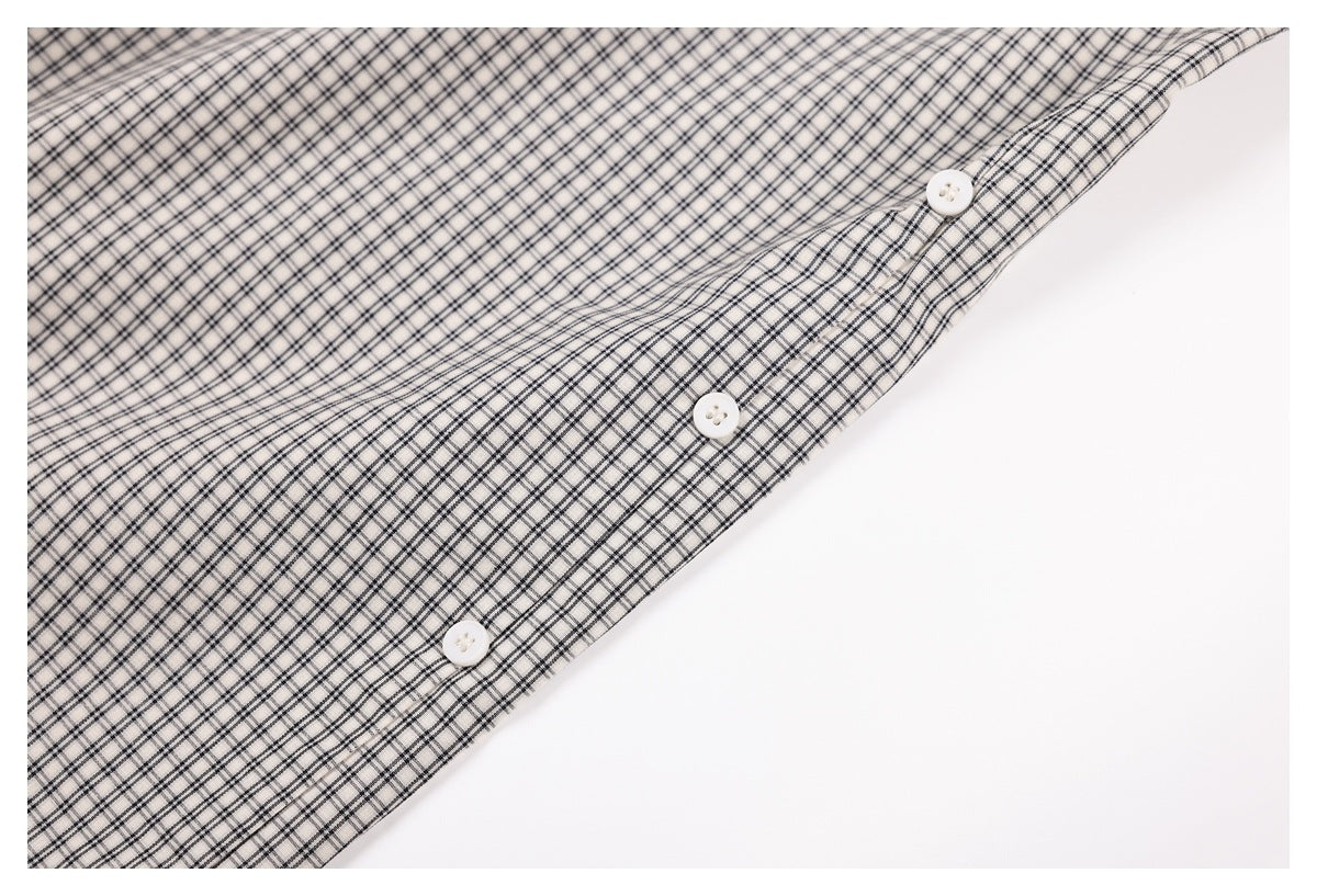 Close-up of white fabric with a fine black check pattern and three white buttons.