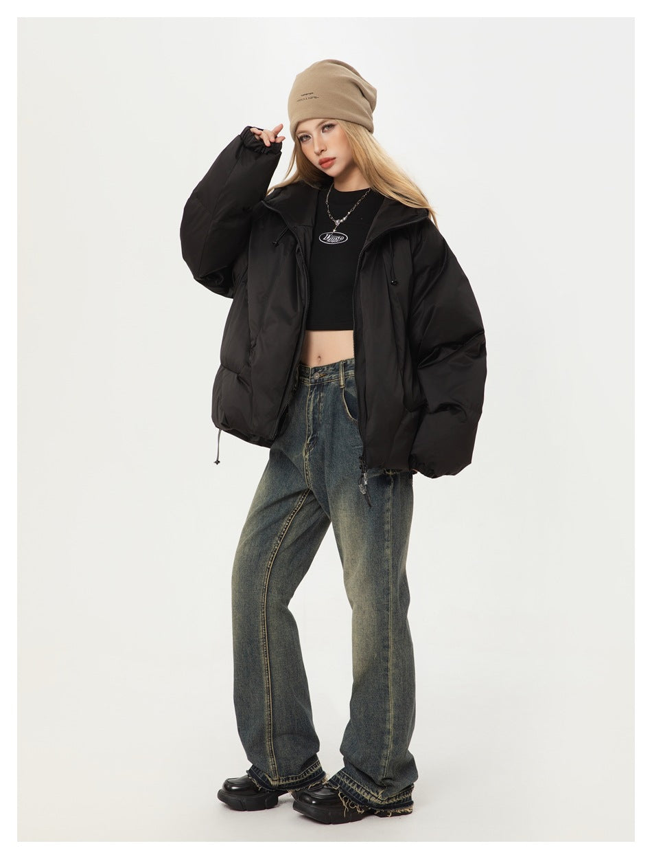 Model wearing an oversized black puffer jacket with a beanie, cropped black top and faded wide-leg jeans