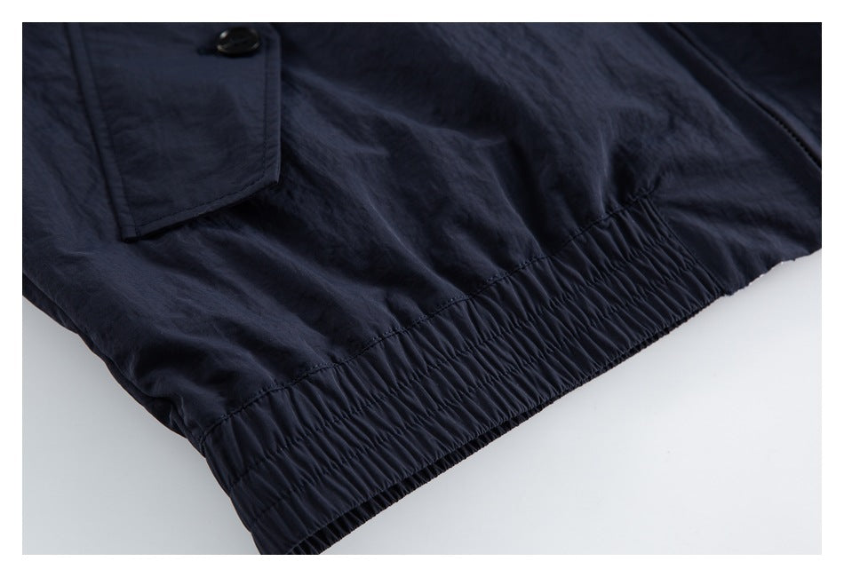 Close-up of a gathered elastic hem and flap pocket on a dark navy garment.