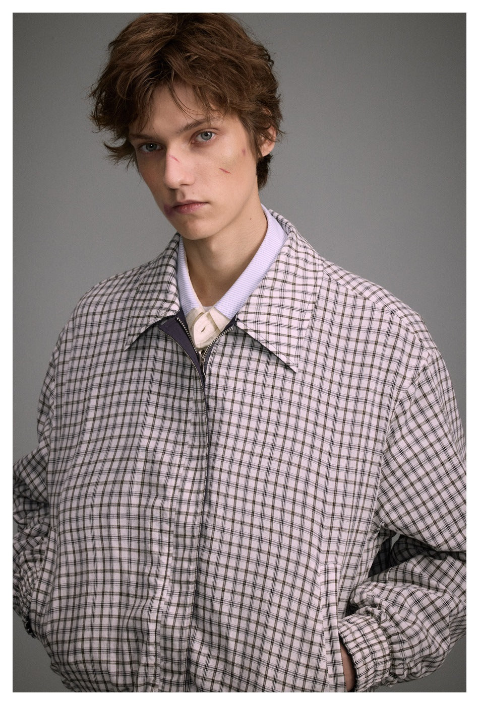 Close view of a model wearing a light plaid jacket with a wide collar and visible front zipper.